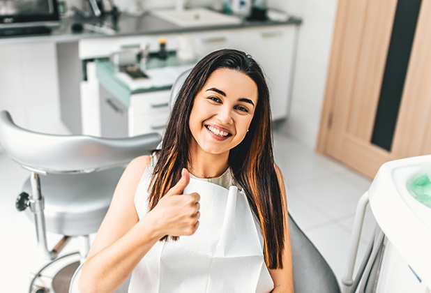Woman in dental chair smiling and giving thumbs up