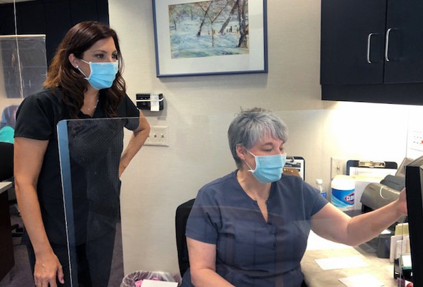 Two dental team members in consultation area wearing protective gear