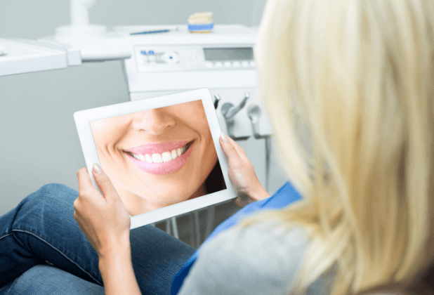 Woman looking at virtual smile design image on tablet computer