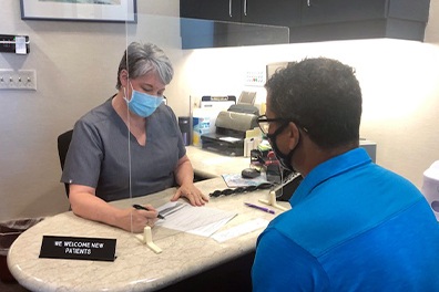 Dental team member and patient wearing safety gear during consultation